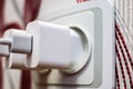 Two modern white cell phone chargers plugged into the socket. Energy waste concept.