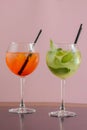 Two mojito alcohol cocktails with plastic straw, tropical beverage with ice, mint and lime on pink background copy space Royalty Free Stock Photo