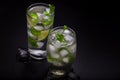 Two mojito cocktails on a dark background