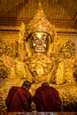 Two monks praying by the golden Buddha statue, Myanmar (Burma)
