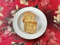 Two Moon cake with Red Bean on gold velvet with a magnolia flower pattern red background. Royalty Free Stock Photo