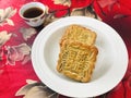 Two Moon cakes with Red Bean served with tea, on red gold velvet with a magnolia flower pattern background. Royalty Free Stock Photo