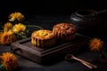 two moon cakes sitting on a wooden tray next to yellow flowers and a vase of daisies on a dark background with a spoon and a Royalty Free Stock Photo