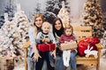 Two mothers sitting with cute kids and holding christmas presents. Royalty Free Stock Photo