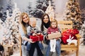 Two mothers sitting with cute kids and holding christmas presents. Royalty Free Stock Photo