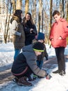 Two mothers talking during their children play with snow in winter park