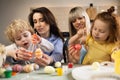 Two mothers with their children color eggs in preparation for Easter.