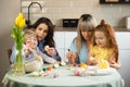 Two mothers with their children coloring Easter eggs. Royalty Free Stock Photo