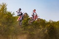 two motocross riders jump off a dirt track and jump over the trees Royalty Free Stock Photo