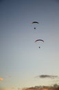 Two Motorized Hang Glider Flying Away in the Evening Sky Royalty Free Stock Photo