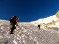 Two mountain climbers headed to a high alpine peak over a steep glacier