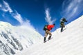 Two mountain trekkers on steep snowed hill with dramatic sky background Royalty Free Stock Photo