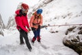 Two mountaineers discussing safety abseiling procedures before rappeling down a snowy chutte, on a difficult Winter route