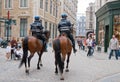 Two mounted policemen patrol the street in center