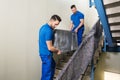 Two Movers Carrying Furniture On Staircase Royalty Free Stock Photo