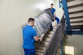 Two Movers Carrying Furniture On Staircase Royalty Free Stock Photo