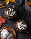 Two mugs of aroma hot chocolate with marshmallows on a dark background with autumn maple leaves, cookies and gray scarf. Concept