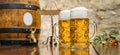 Two mugs of beer with foam and wooden barrel stand on the table, Oktoberfest, Munich, Germany Royalty Free Stock Photo