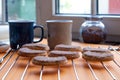 Two mugs of coffee and semilunar sugared cookies on a metal grate