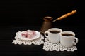 Two mugs of coffee, Turkish delight and cherry pots on a black background