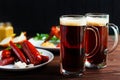 Two mugs of dark beer with crusty grilled chicken wings and vari Royalty Free Stock Photo