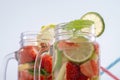 Two mugs with fruit refreshing water from strawberries, lemon, mint and lime in the background of drinking tubes Royalty Free Stock Photo