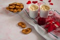 Two mugs of hot coffee with marshmallow, cookies in the form of hearts, a box for a jewelry gift and decorative hearts on a pink m Royalty Free Stock Photo