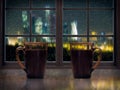 Two mugs with a hot drink - tea or coffee on the window sill of the window. Outside, the night, the city lights, rain, drops on Royalty Free Stock Photo