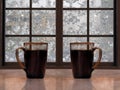 Two mugs with a hot drink - tea or coffee on the window sill of the window. Outside, winter, snow, snow patterns on glass
