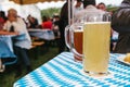 Two mugs with a light and dark beer stand on the table. In the background, blurred people. Celebrating the traditional Royalty Free Stock Photo