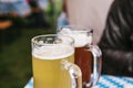 Two mugs with a light and dark beer stand on the table. Celebrating the traditional German beer festival called Royalty Free Stock Photo