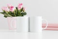 Two mugs mockup with books and pink roses in a pot on a white table