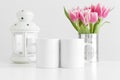 Two mugs mockup with pink tulips in a pot and candle holder on a white table