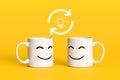 Two mugs smiling and sharing a good idea on a yellow background Royalty Free Stock Photo