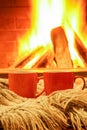Two colorful mugs for tea or coffee; wool things near cozy fireplace.