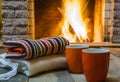 Two mugs for tea or coffee, woolen things near cozy fireplace. Royalty Free Stock Photo