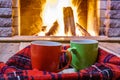 Two mugs for tea or coffee, woolen things near cozy fireplace. Royalty Free Stock Photo