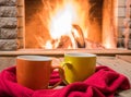 Two mugs for tea, wool things near cozy fireplace. Royalty Free Stock Photo