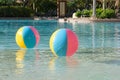 Two multi-colored beach balls float in the water of a resort swimming pool on a summer day Royalty Free Stock Photo