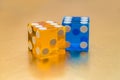 Two multi-colored glass dice on a gold background. The yellow six and the blue six are behind. Royalty Free Stock Photo