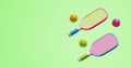 Two multi-colored pickleball rackets with balls on a green background. Sports games set 3D rendering