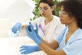 Two multi-ethnic female lab scientists in protective uniform carrying out experiments in laboratory Royalty Free Stock Photo