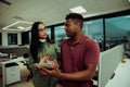 Two multi-ethnic partners discussing matters while holding digital tablet standing in office space Royalty Free Stock Photo