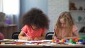 Two multi-racial girls drawing with colorful pencils in early education center