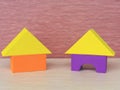 Two multicolored yellow, purple, orange house of building blocks triangle, rectangle, a children educational toy on a pink bac