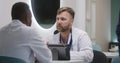 Two multiethnic doctors sit in hospital cafeteria, discuss work Royalty Free Stock Photo