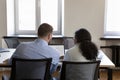 Two multiethnic employee men sharing laptop at table