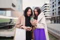 Two multiethnic happy young women surprised about the sales and offerts looking a cell phone doing online shopping Royalty Free Stock Photo