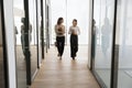 Two multiethnic office employees women walking on hallway