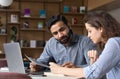 Two multiethnic professionals working together with laptop in office.